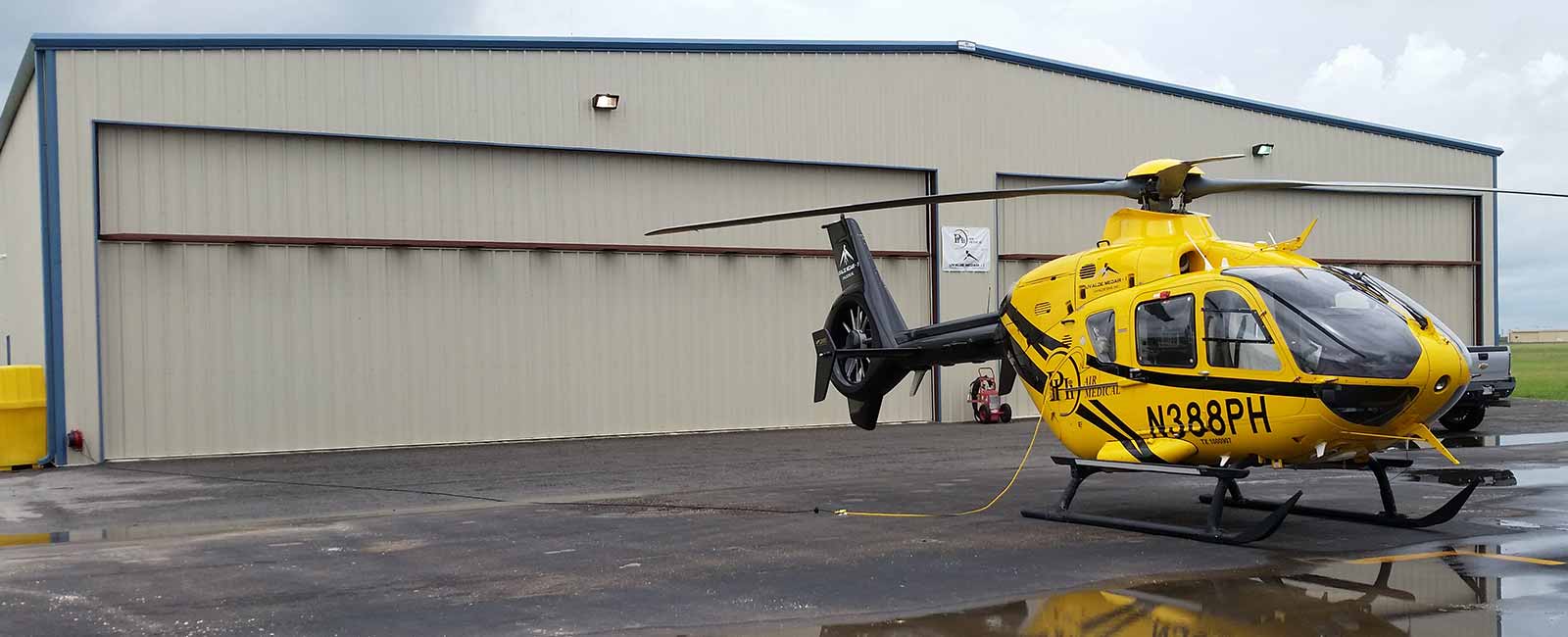 Exterior photo of a Hangar wiith a helicopter parked outside
